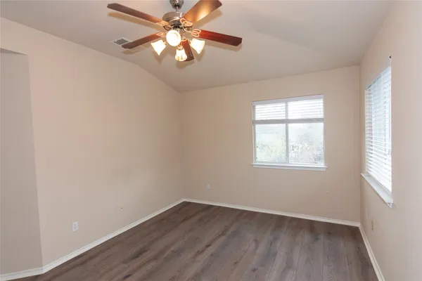an empty room with wooden floor fan and windows