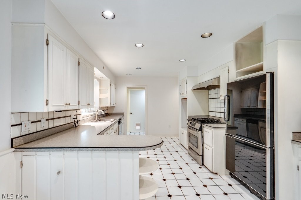 3060 Chamberlain Road Akron, OH 44333 - Photo 15 of 47 Kitchen featuring kitchen peninsula, light tile flooring, gas stove, backsplash, and white cabinetry