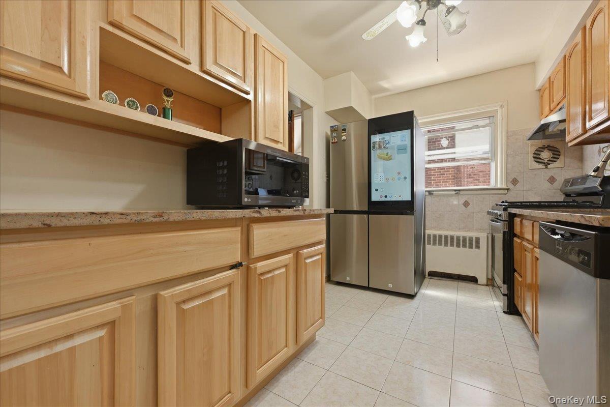 79 Wellington Road Elmont, NY 11003 - Photo 9 of 33 Kitchen featuring natural wood cabinetry, stone-finish countertops, stainless steel appliances, and tiled flooring