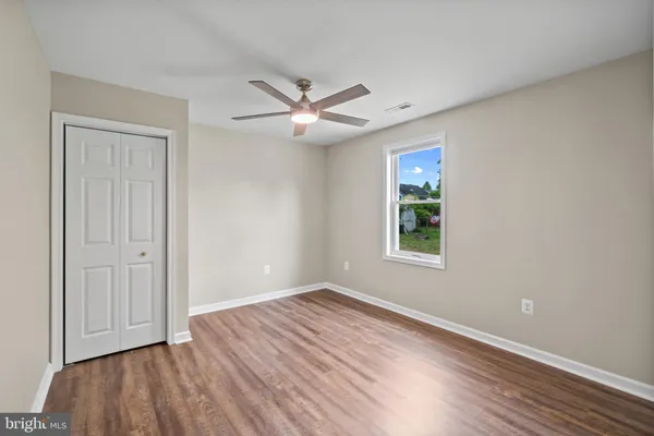 an empty room with wooden floor ceiling fan and windows
