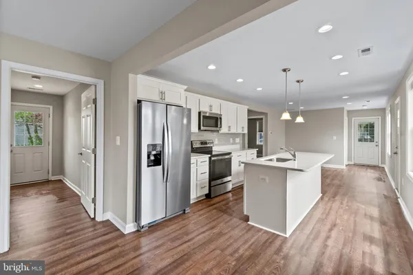 a large kitchen with a center island wooden floor stainless steel appliances and a window