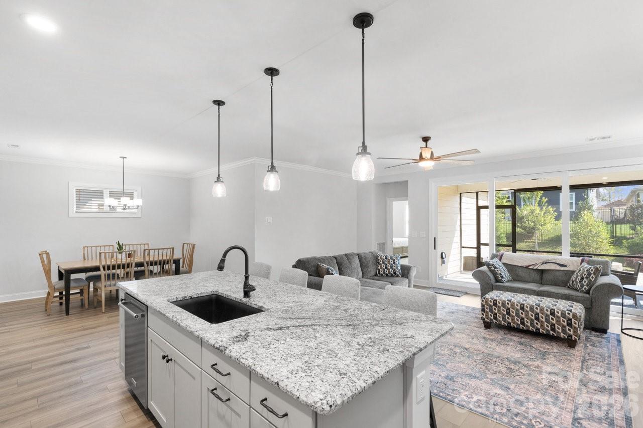a kitchen with stainless steel appliances granite countertop a sink a stove and chairs with wooden floor