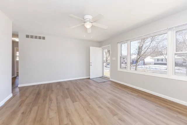 a view of an empty room with wooden floor and a window