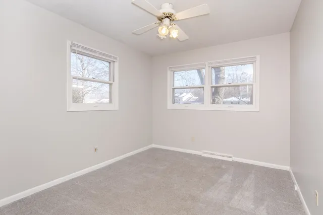 an empty room with a window and a fan