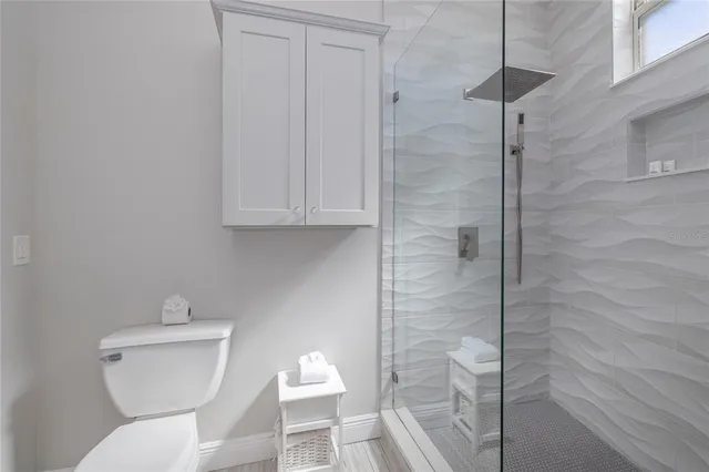 a spacious bathroom with a granite countertop sink a toilet a mirror and shower