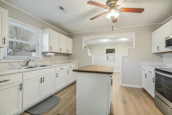 a kitchen with granite countertop a sink a counter space appliances and cabinets