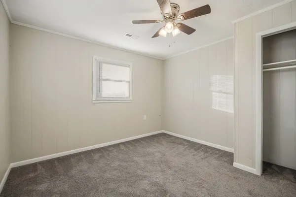 an empty room with a window and a fan