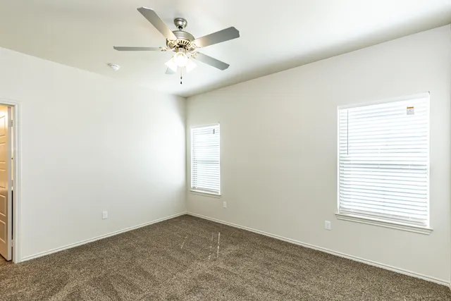 an empty room with a window and a fan