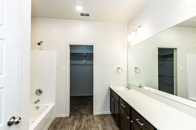 a bathroom with a double vanity sink a mirror and a bathtub