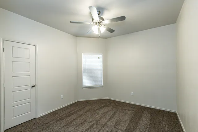 an empty room with fan and windows