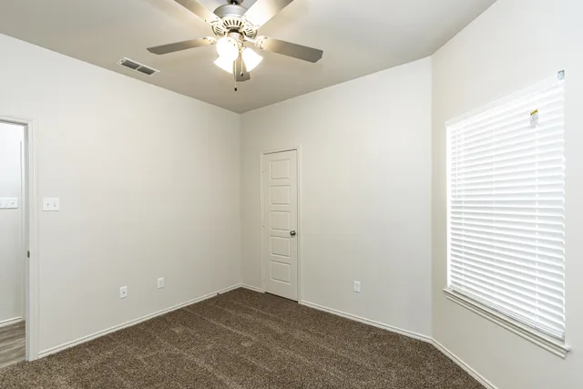 an empty room with a window and a fan