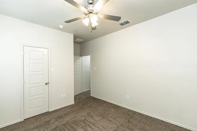 an empty room with closet and a chandelier fan