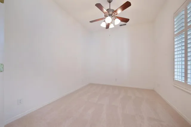 an empty room with a window and a fan
