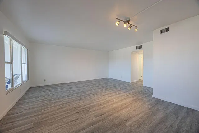 a view of an empty room with wooden floor and a window