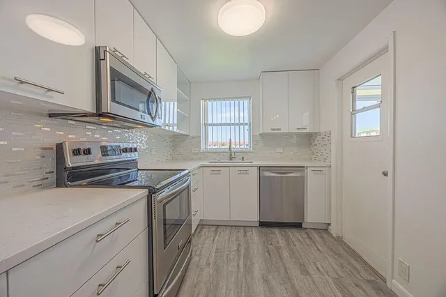 a kitchen with sink a microwave and cabinets