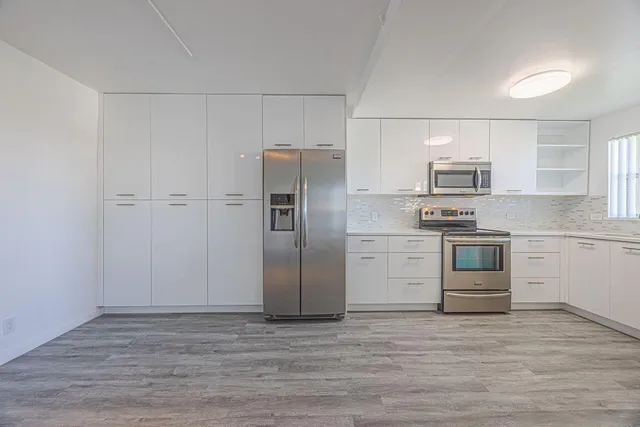 a kitchen with granite countertop a refrigerator stove and wooden floor