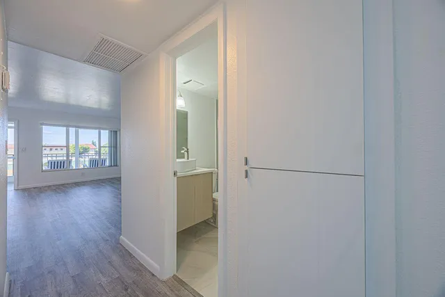 a view of a hallway with wooden floor and cabinet