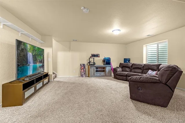 a living room with furniture a flat screen tv and a window