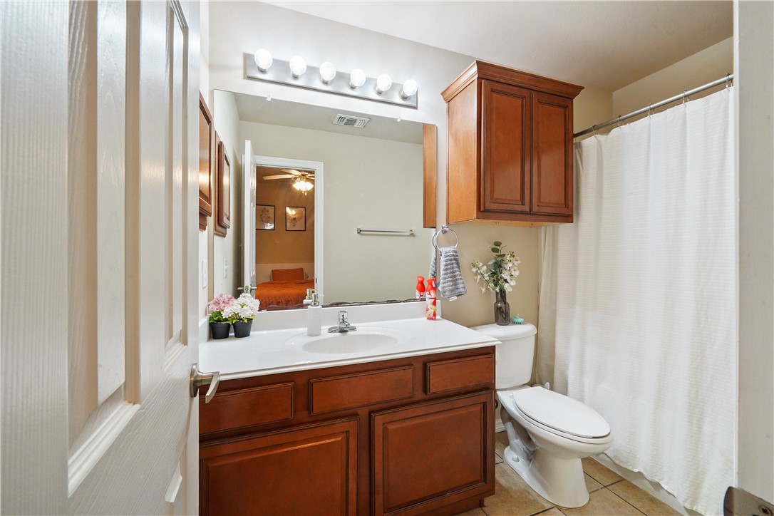 1198 Jones-Butler Road College Station, TX 77840 - Photo 18 of 21 Ensuite bathroom featuring light tile patterned flooring, vanity, a ceiling fan, and a shower with shower curtain