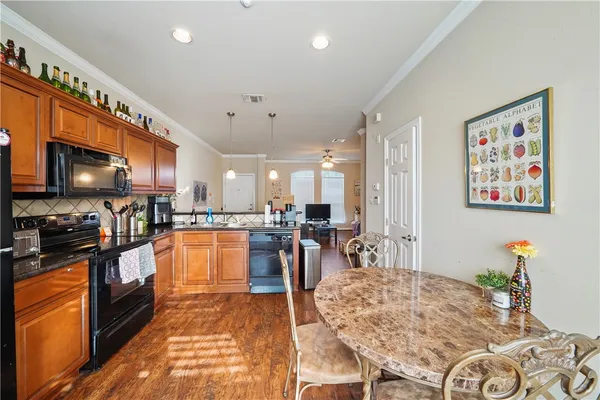 a living room with stainless steel appliances furniture a flat screen tv and kitchen view