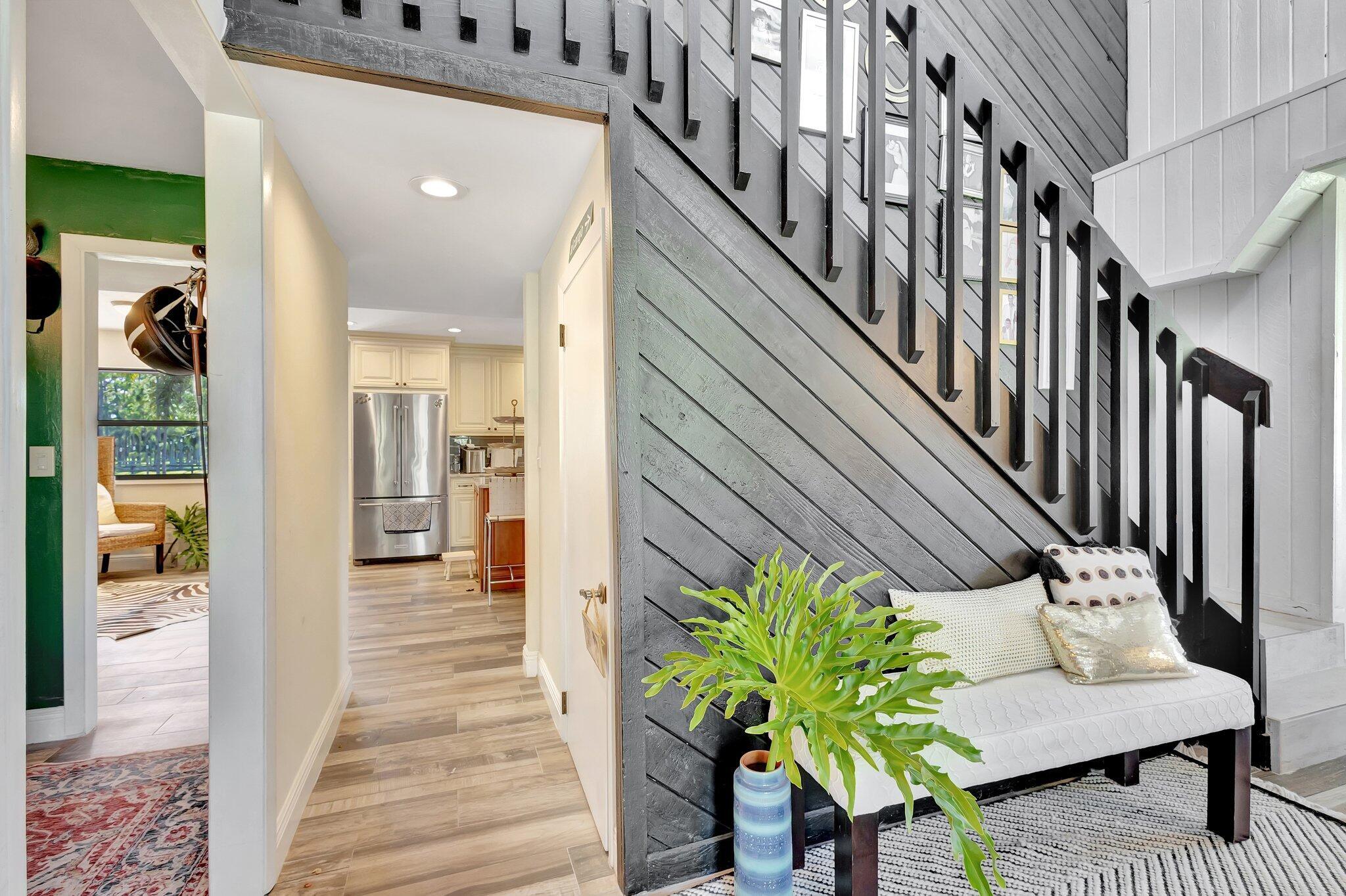 5446 Reynolds Road Lake Worth, FL 33449 - Photo 4 of 57 a hallway with wooden floor stairs and a potted plant