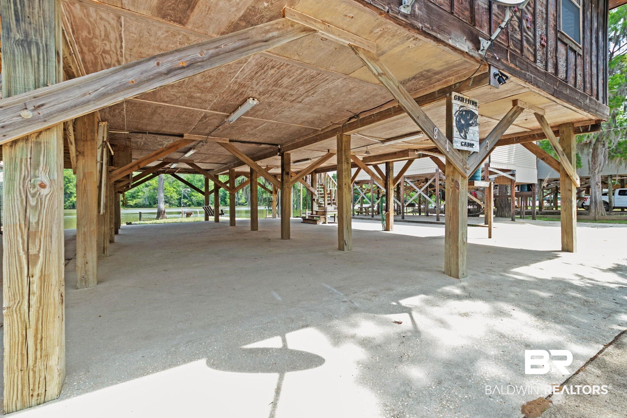 8153 Bryant's Lndg Road Stockton, AL 36579 - Photo 66 of 87 Elevated property featuring substantial wooden pilings, an expansive concrete pad, exposed wood ceiling, and fluorescent overhead lighting