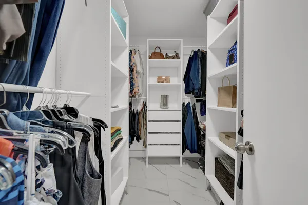 a view of walk in closet with clothes and shoes