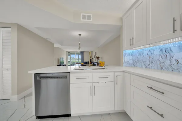 a kitchen with white cabinets and sink