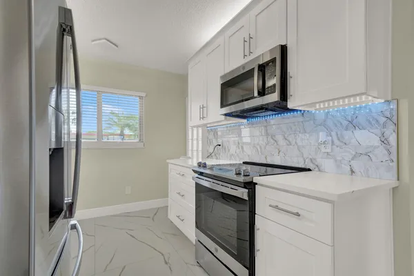 a kitchen with stainless steel appliances granite countertop white cabinets a microwave oven and a refrigerator