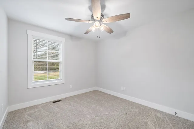 an empty room with a window and a fan