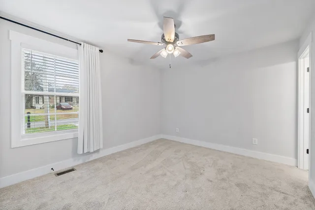 an empty room with windows and fan