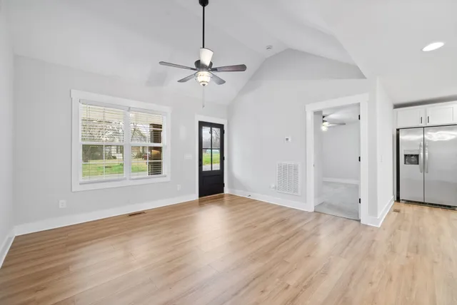 a view of an empty room with window and wooden floor