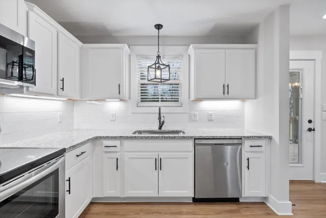 a kitchen with granite countertop white cabinets and white appliances