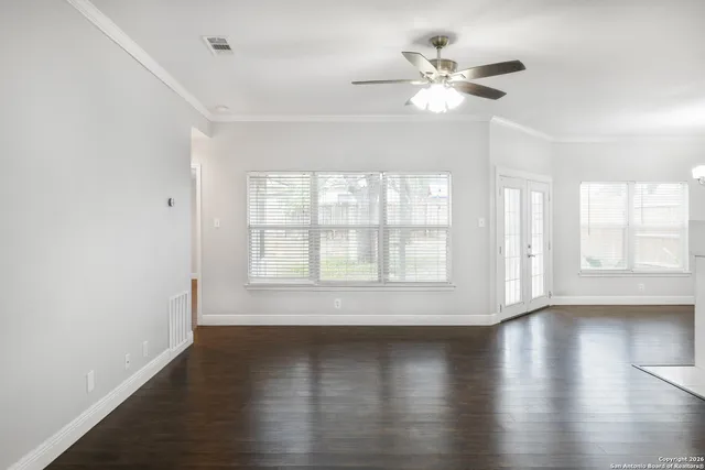 an empty room with wooden floor and windows