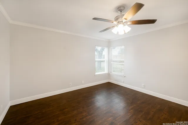 an empty room with wooden floor fan and windows
