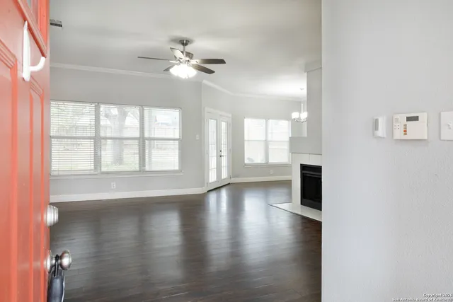 a view of an empty room with wooden floor and a window