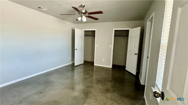 an empty room with closet and a ceiling fan
