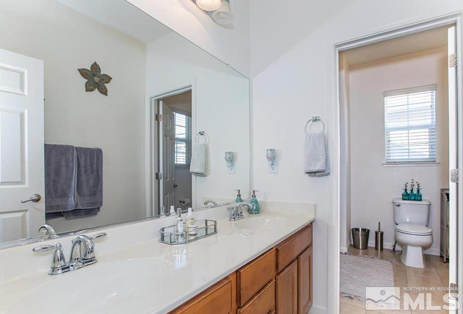 6923 Sacred Circle Sparks, NV 89436 - Photo 12 of 16 a bathroom with a granite countertop sink a toilet and a mirror