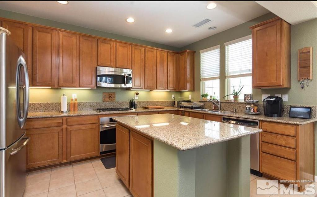 6923 Sacred Circle Sparks, NV 89436 - Photo 9 of 16 a kitchen with stainless steel appliances granite countertop a sink stove refrigerator and cabinets