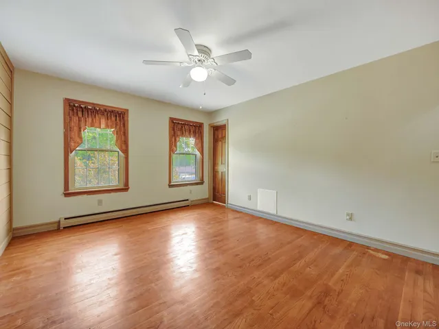 an empty room with wooden floor chandelier fan and windows