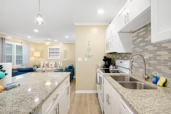a kitchen with stainless steel appliances granite countertop a sink a stove and a wooden floors