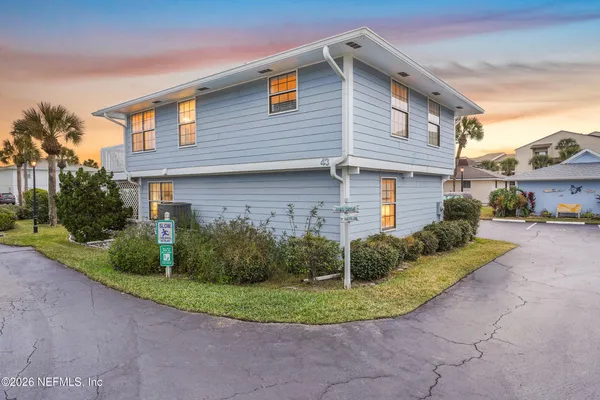 a view of a brick house with a yard plants next to a road