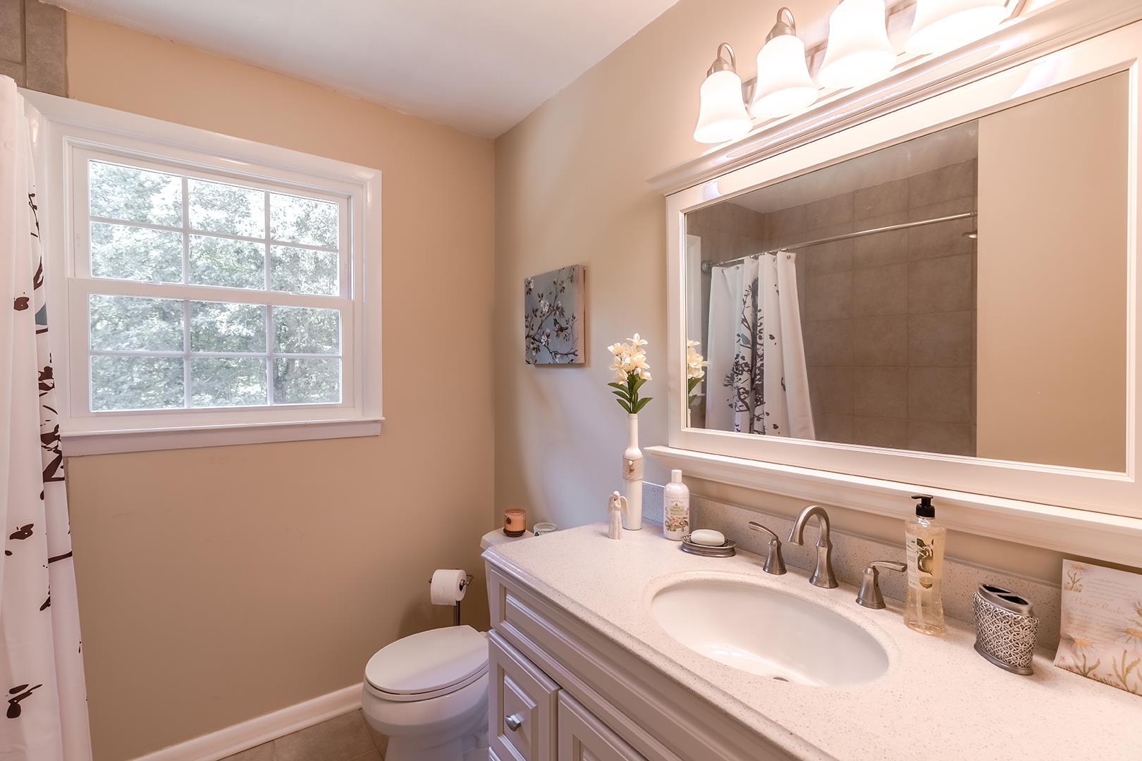 7574 King Road Fairview, TN 37062 - Photo 22 of 30 a bathroom with a granite countertop toilet a sink a mirror and a window