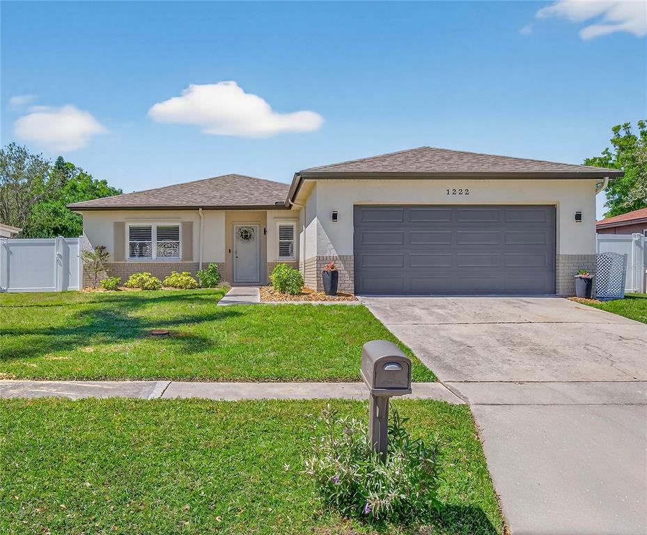 1222 Ranchwood Drive East Dunedin, FL 34698 - Photo 1 of 1 a front view of a house with a yard and garage