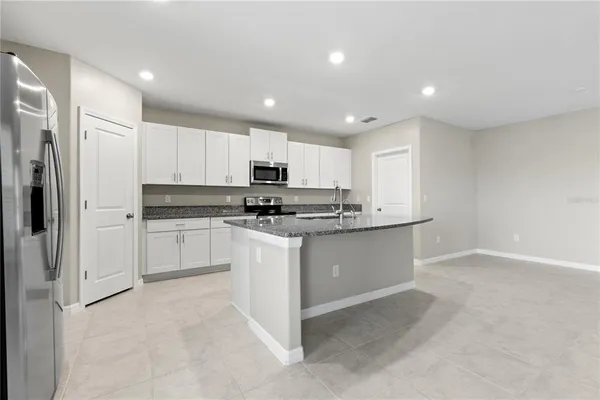 a view of kitchen with granite countertop cabinets and refrigerator