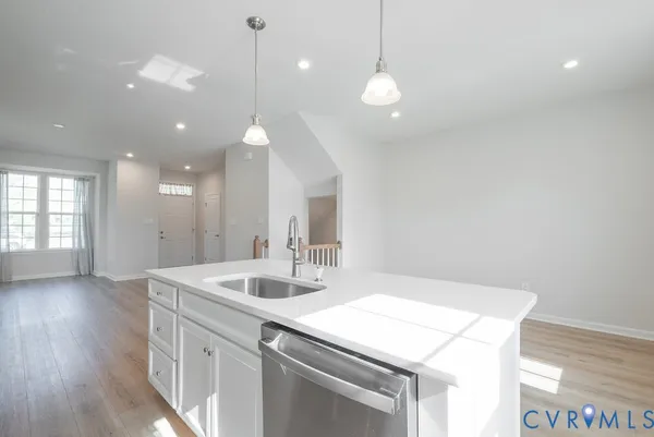 a large white kitchen with lots of counter space a sink appliances and cabinets