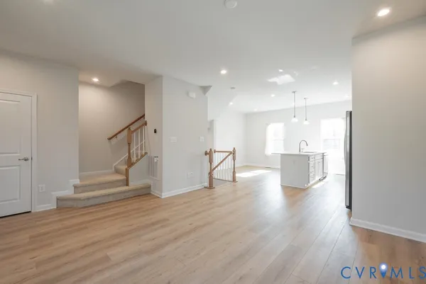 a view of empty room with wooden floor and kitchen