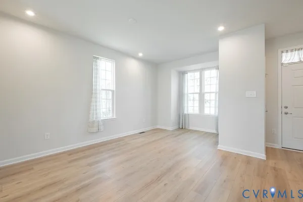 an empty room with wooden floor and windows