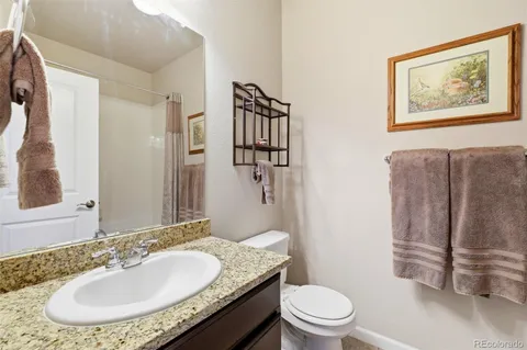 a bathroom with a granite countertop sink toilet and a mirror