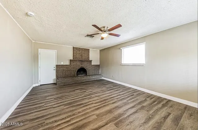 a view of empty room with fireplace and wooden floor